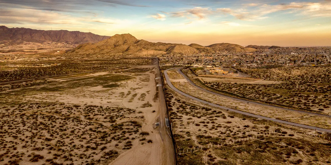 Mexico-US border in Arizona. Landscape shows desert and a wall partitioning the middle of the desert.